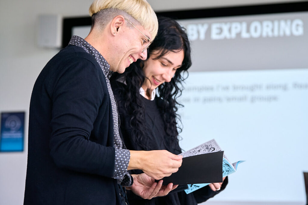 Two individuals examining a book together in a classroom setting.